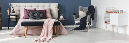 White and grey bedroom with pink bed with quilted headboard