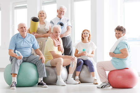 Older people smiling and posing for a photo at the gymの写真素材