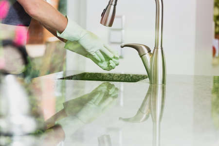Woman removes green rubber gloves over the sink after cleaning furnitureの写真素材