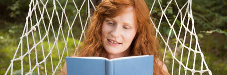 Young woman relaxing and reading a book in hammockの写真素材