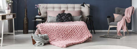 Thick wool pink blanket on cozy bed in stylish bedroom