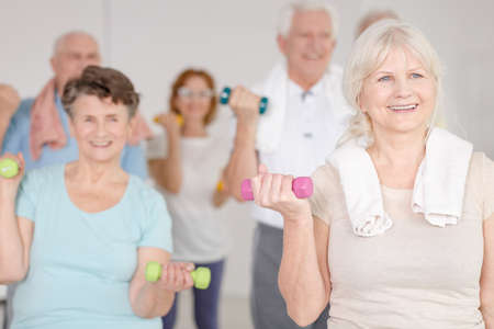 Elder happy people working out with colorful dumbbellsの写真素材