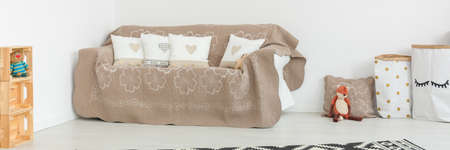 Beige sofa with pretty pillows in modern white baby room