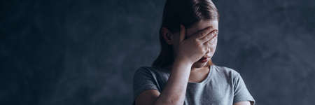 Sad, and lonely girl covering her eyes with her handの写真素材