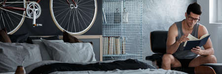 Young handsome man reading a book in his apartmentの写真素材