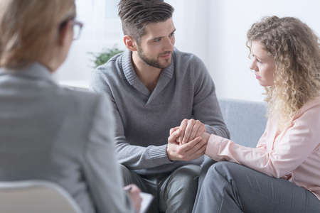 Husband apologizing to his wife during couple therapyの写真素材