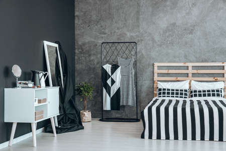 Black overlay on mirror with white frame and white commode against black wall
