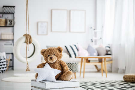 Cute teddy bear toy in white scandinavian playroom with swingの写真素材