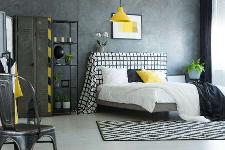 Brass chair in stylish bedroom with white flowers on bolster of king-size bedの写真素材