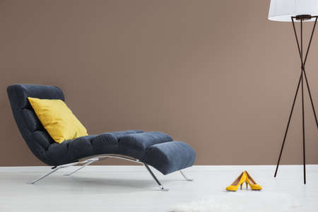 Black chaise lounge with yellow pillow, yellow high heels and modern lampの写真素材