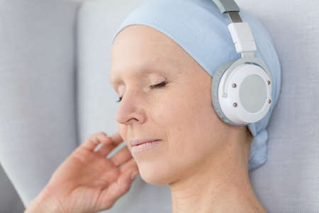 Sick woman with scarf on her head listening to musicの写真素材