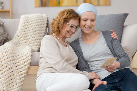 Smiling woman suffering from cancer holding old photographyの写真素材