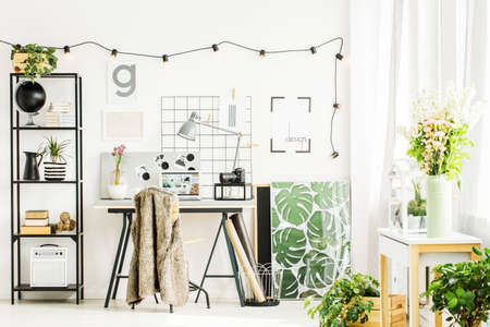 Glossy picture with natural motive next to white and black tube in stylish office room. Home office...