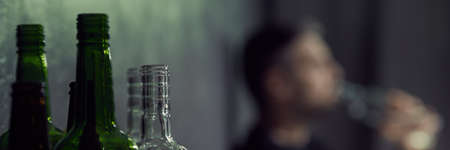 Glass bottles and blur image of man drinking alcohol, panoramaの写真素材