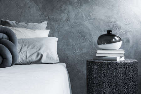 Gray decor bedroom close-up, textured wall, openwork table, books and vaseの写真素材