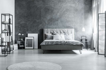 Modern bedroom with simple furniture, gray bedding and soft headboardの写真素材