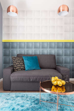 Living room interior in elegant style with copper coffee table, lamps and decorative black and blue cushions on cozy gray sofaの写真素材