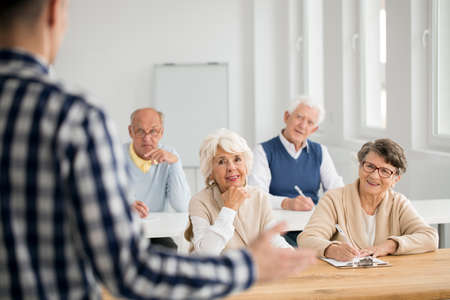 Elder women and men making notes from IT lecturesの写真素材