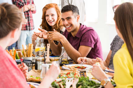 Smiling man in violet shirt eats slow food with happy vegetarians in vege restaurantの写真素材