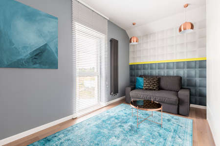Contemporary stylish room with gray couch, blue abstract artwork, coffee table, square molding and decorative pillowsの写真素材