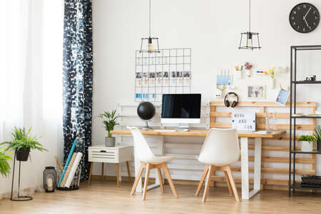 Modern, minimalistic office with personal photos on the wall for a creative freelancerの写真素材