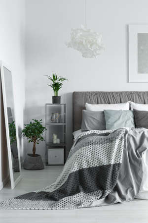 Blanket with dots falling off the king-size bed in white roomの写真素材