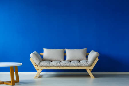 Minimal interior with a wooden small table, and a cozy looking modern couchのeditorial素材