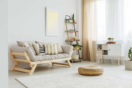Material pouf on white carpet in front of grey sofa with patterned pillowsの写真素材