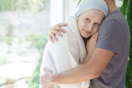 Loving husband hugging hopeful woman with cancer after successful chemotherapyの写真素材
