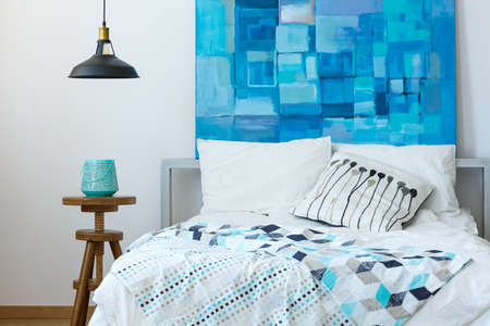 Bright inspiring bedroom with modern blue artwork above the bed