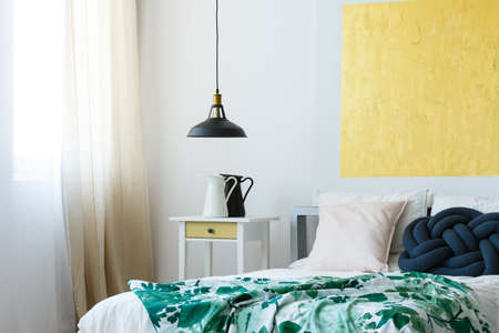 Vintage enamel jugs on bedside table in artistic designed bedroomの写真素材