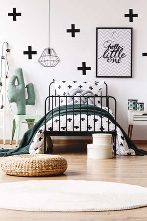 Braided pouf and white carpet in kids room with grey pillow on bed against trendy wallpaperの写真素材
