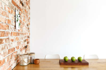 Three green apples on the table with glass jars in dining room with brick wallの写真素材