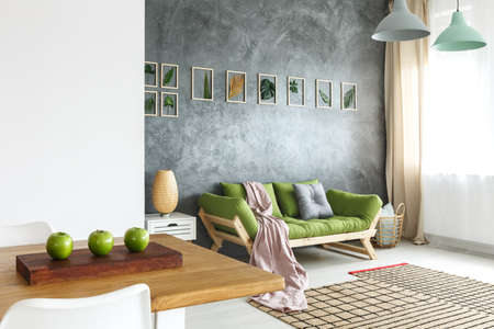 Wooden table with three green apples in the living room with raw wall