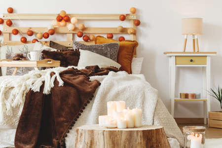 Many white candles standing on a tree trunk in bedroom