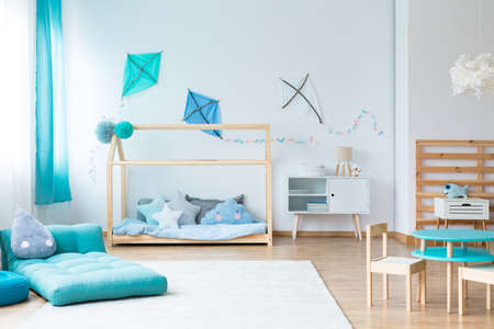 Drop shaped pillow on blue mattress on white carpet in colorful kids bedroom with blue kites on wallの写真素材