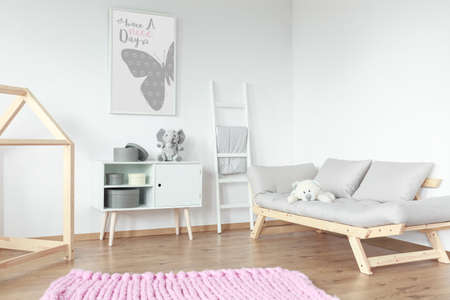 Wooden elements in scandinavian style kid room with pink braided carpet on floorの写真素材