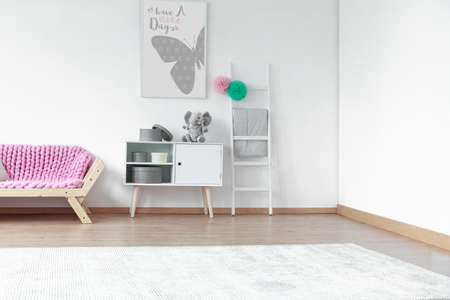 Big white carpet in scandinavian style kid room with pink blanket on wooden sofaの写真素材