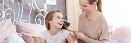 Young mum and her happy daughter having talks and gossip in bedの写真素材