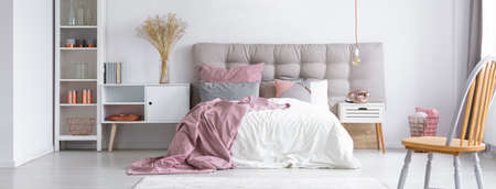 Modern trendy furniture in a cozy minimalist bedroom with copper accessories and pastel pink accents