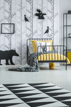 Black and white geometric carpet in cozy child's bedroom with black animal sticker on white...