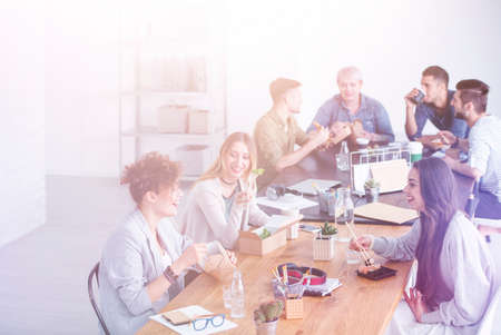 Friends from work eating their delivered lunch at the office deskの写真素材