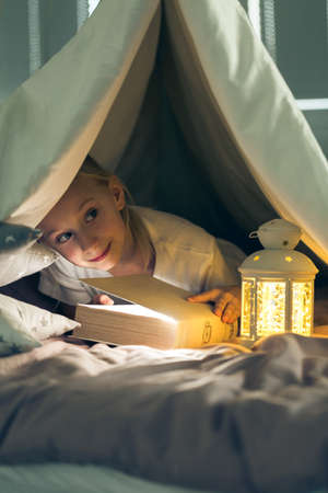 Child reading book in diy indoor tent