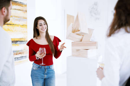 Pretty patron of art talking about painting collection during exhibition in art centerの写真素材