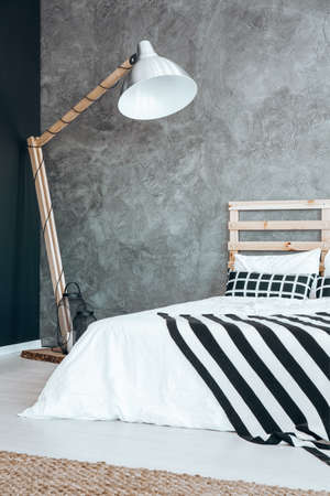 Oversize wooden lamp standing in the corner of dark bedroomの写真素材