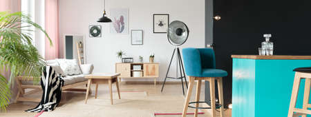 Teal bar stools in a living room standing behind a black wall in an interior housing modern furniture like a stylish sofa or a coffee tableの写真素材