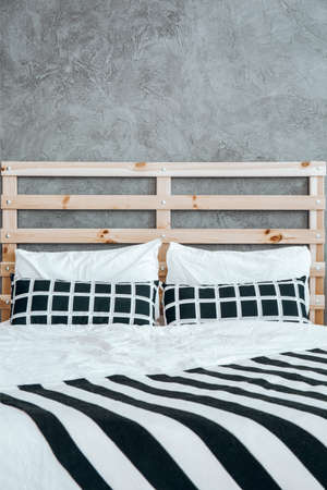 Close-up photo of black and white striped blanket on the bed with cushions