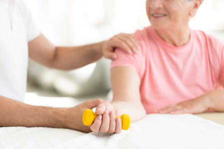 Senior patient committed to an active, isometric exercise session with her physiotherapist at nursing homeの写真素材