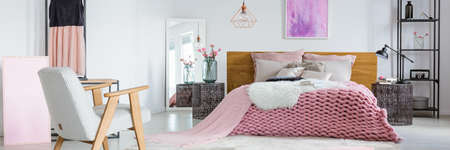 Two books placed on the bed with pink woolen blanket and furry rug in cozy roomの写真素材