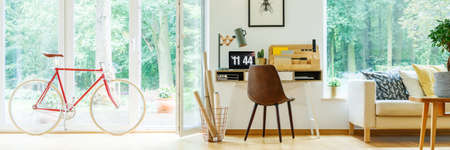 Paper rolls in metal basket standing next to wooden desk with digital clockの写真素材